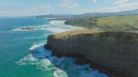 aerial view of steep, rugged and dramatic cliffs and wild, rough ocean with white wash waves at smails beach on the otago peninsula, dunedin, new zealand aotearoa