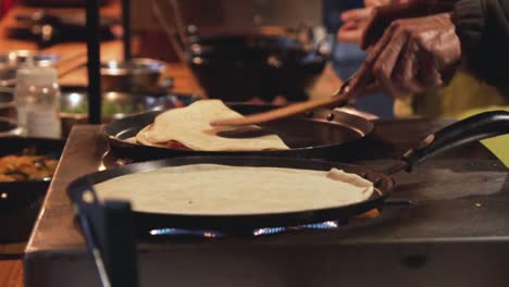 slow motion shot of two pans with crepes in a street market