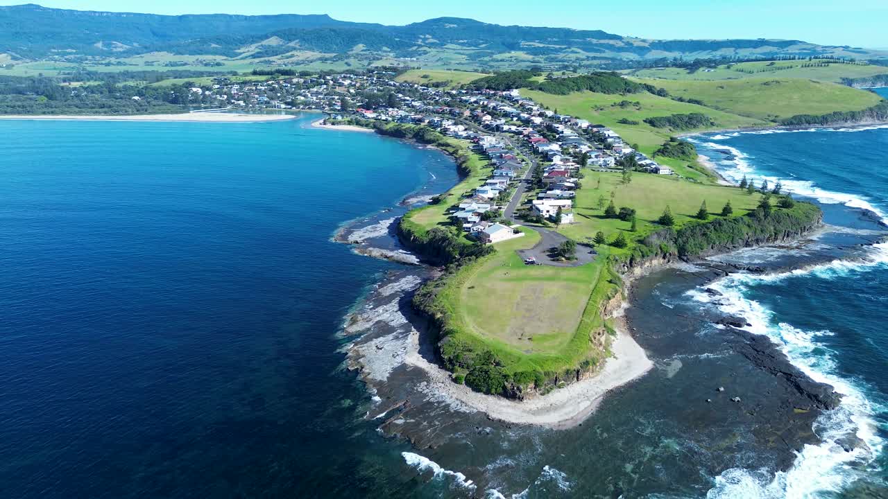 Drone aerial landscape of Gerroa town suburbs with rural housing along streets and a beautiful ocean coastline with waves and headland on South Coast Gerringong Illawarra NSW Australia travel tourism