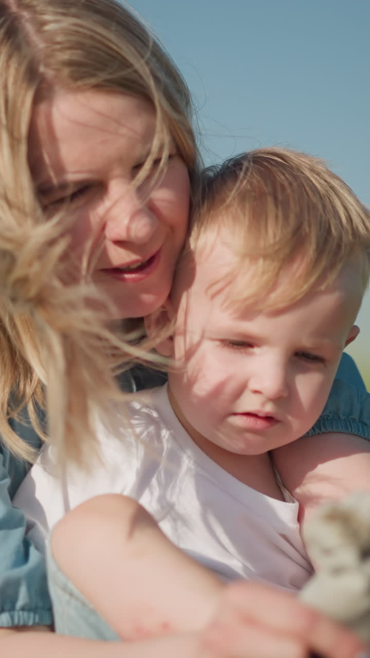 Mother Helping Son Put on Socks in a Sunny Grass Field with love carefully
