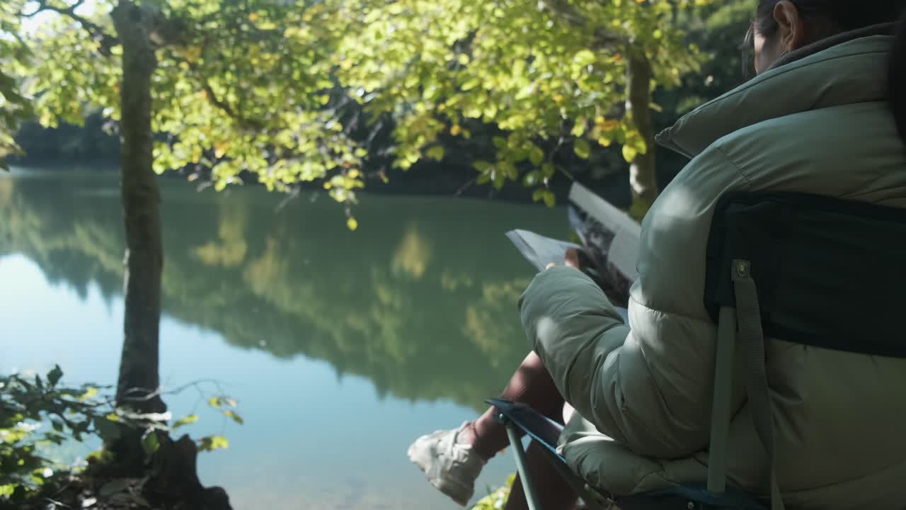 자연 속에서 잡지를 읽고 호수 전망을 즐기는 소녀