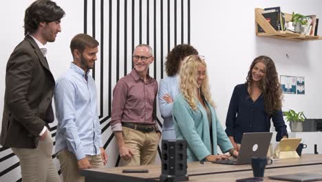 Team applauding for businesswoman after presentation on laptop in office