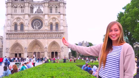 Birds-feed-from-a-young-girls-hand-in-front-of-Notre-Dame-cathedral-in-paris