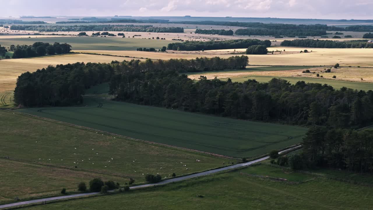 Drone retreats across English countryside, revealing open green fields and surrounding farmland