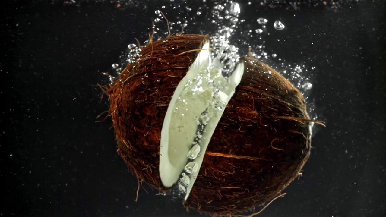 Split Coconut Dropping into Water with Splashes and Bubbles
