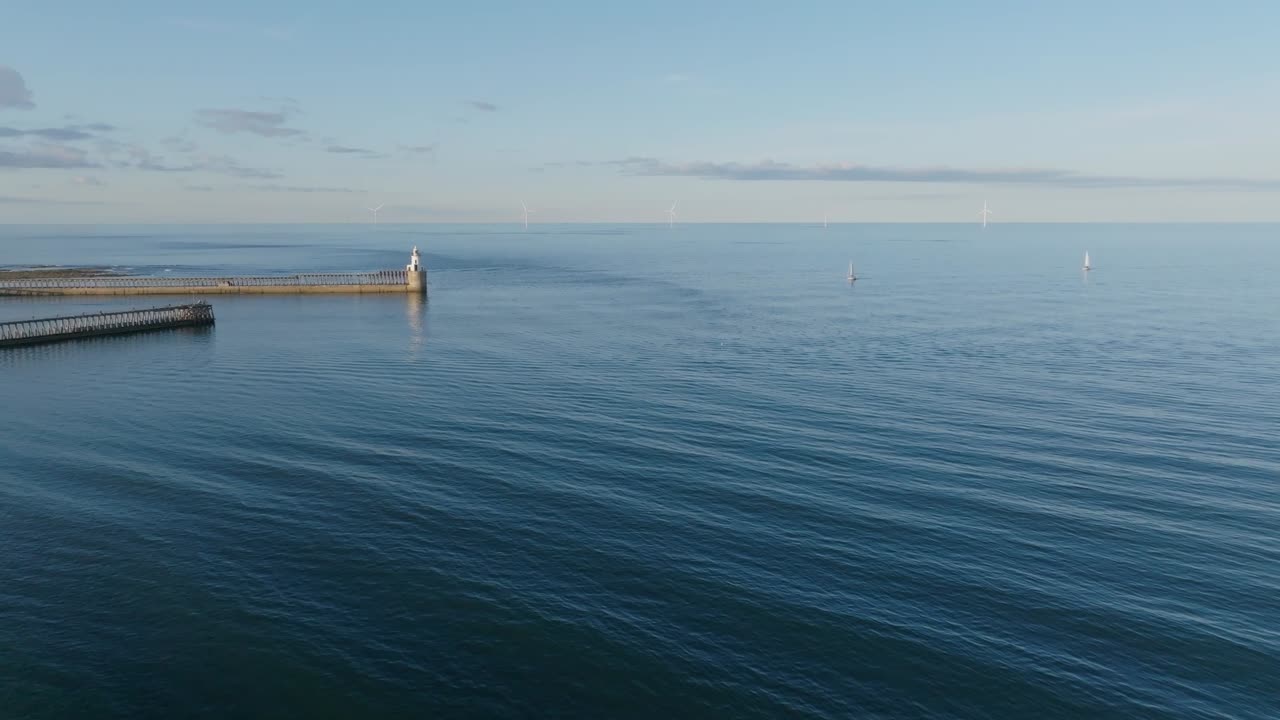 Drone clip showing rippling of sea currents around a harbour on calm summer day