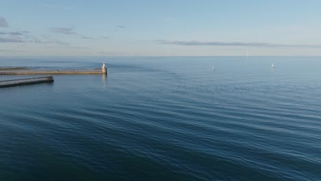 drone clip showing rippling of sea currents around a harbour on calm summer day