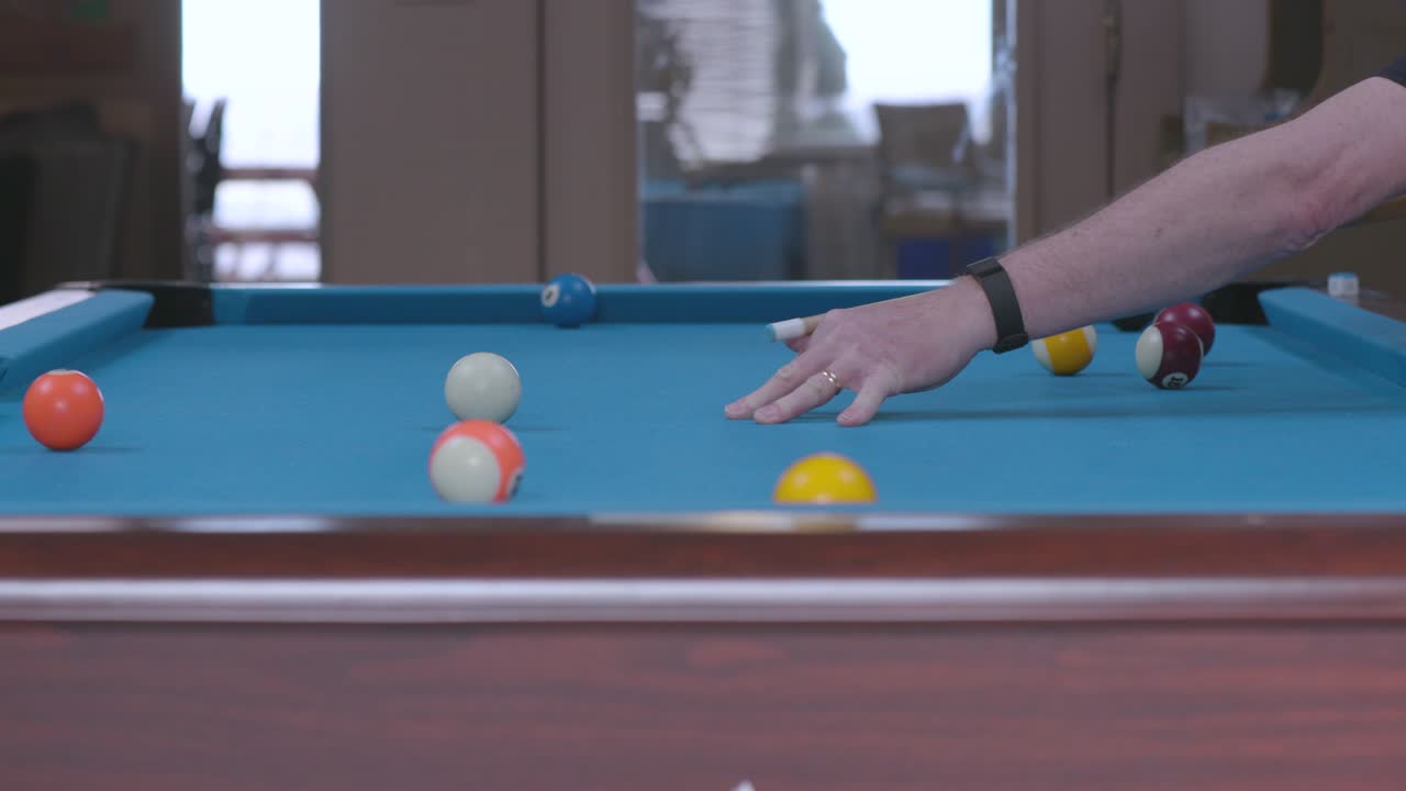 Man Sinking Pool Ball in Side Pocket on Blue Billiards Table