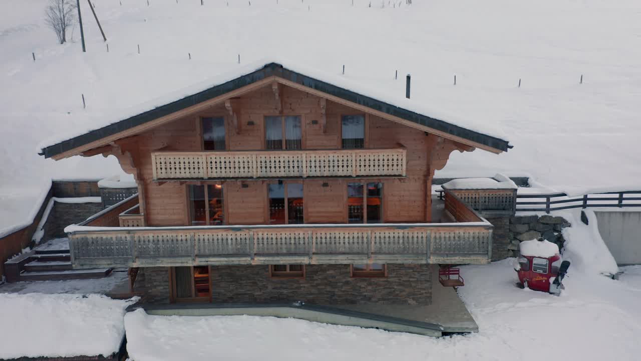 drone volando hacia un lujoso chalet y volando sobre un techo cubierto de nieve