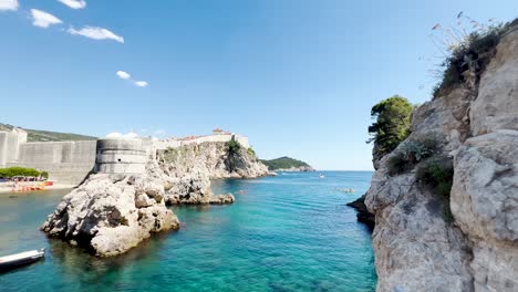 Dubrovnik-West-Harbour-next-to-Fort-Lovrijenac-on-a-beautiful-day-with-kayakers-and-yachts-in-the-distance,-Croatia