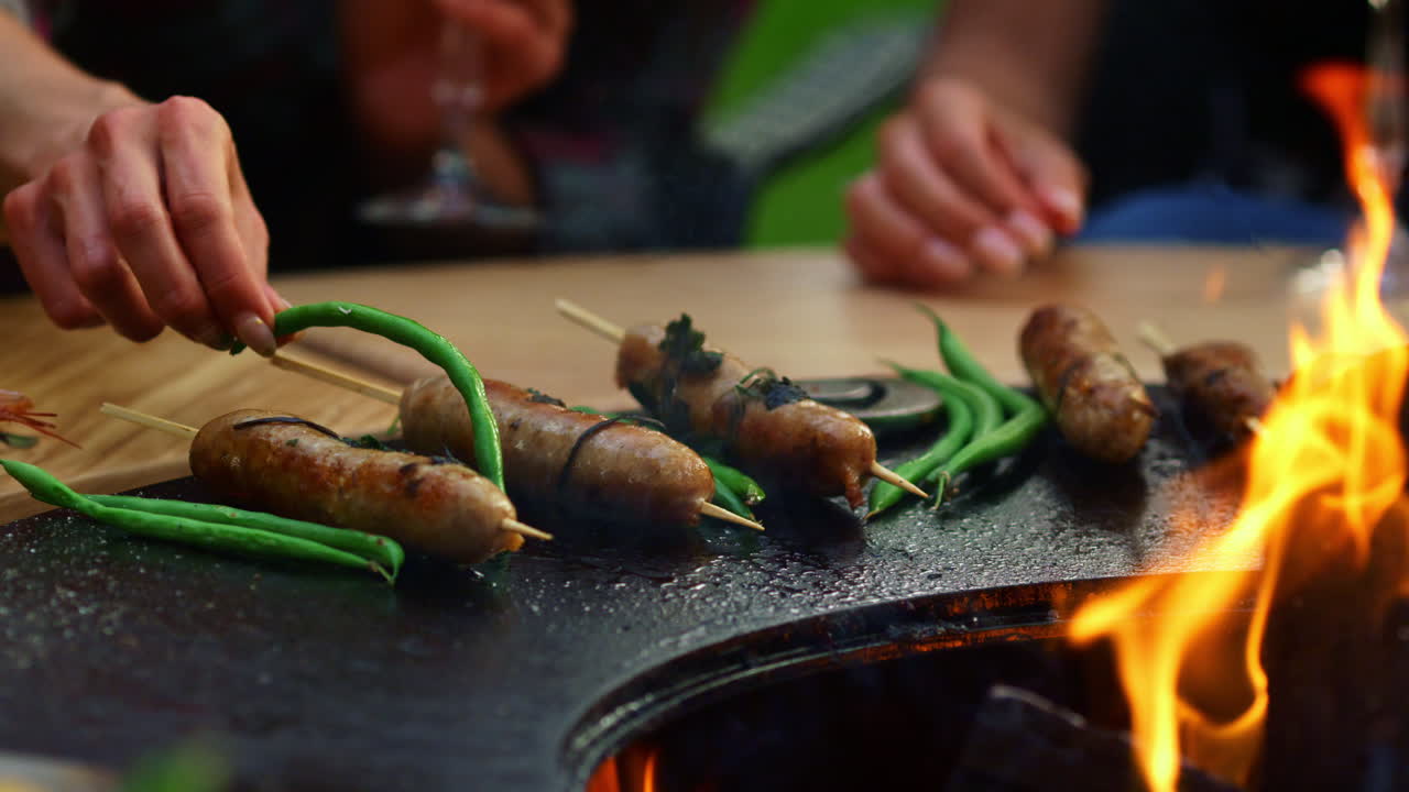 밖에서 소시지를 돌리는 알려지지 않은 여자. 야외에서 bbq 파티를 위해 요리하는 여자