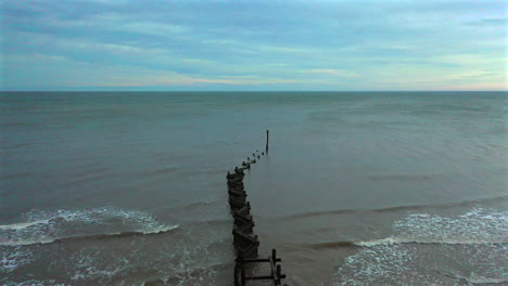 Aerial-flight-out-over-crooked-sea-defences-and-out-to-sea