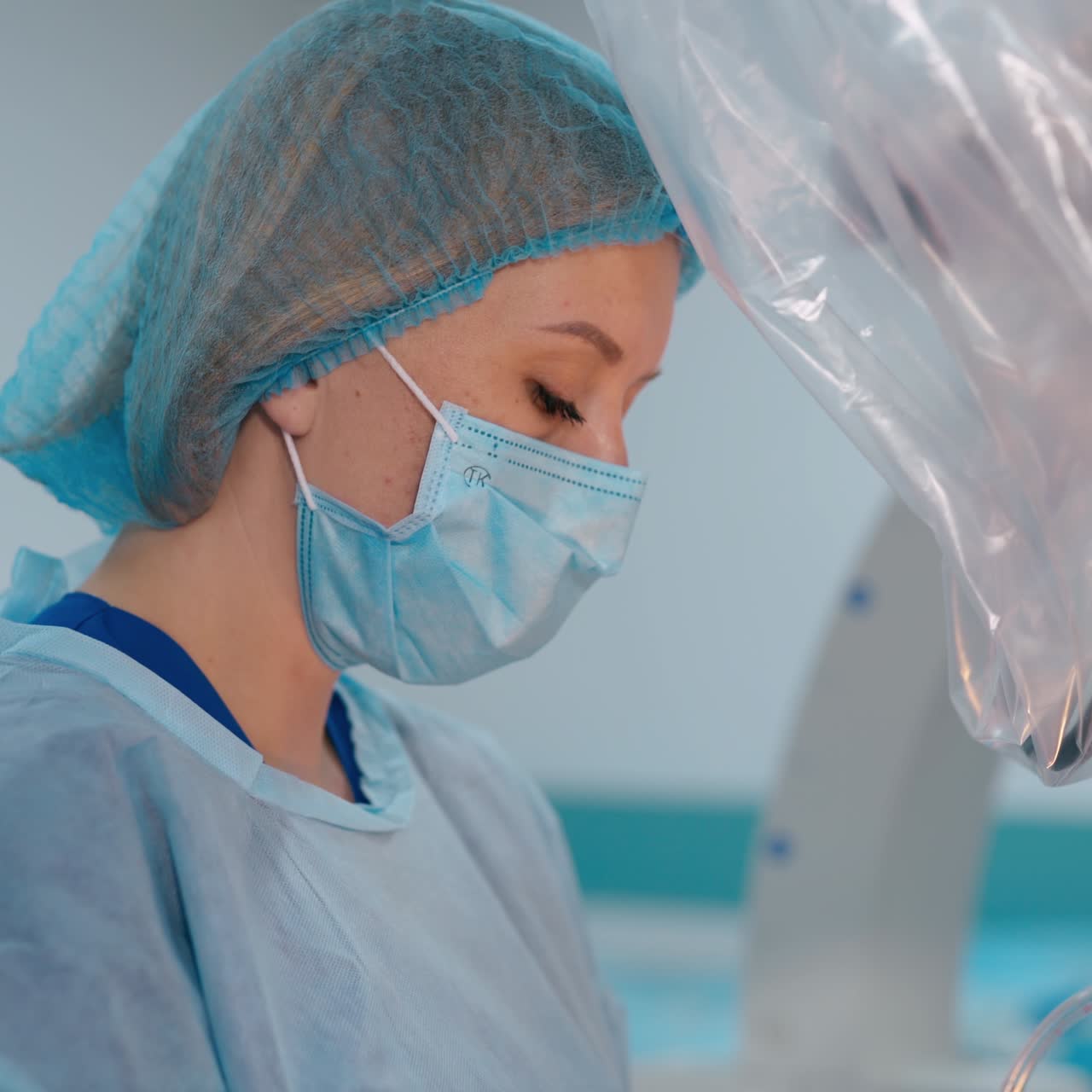 Female doctor wearing protective mask. Side view of woman assistant during the operating process at clinic. Healthcare concept.