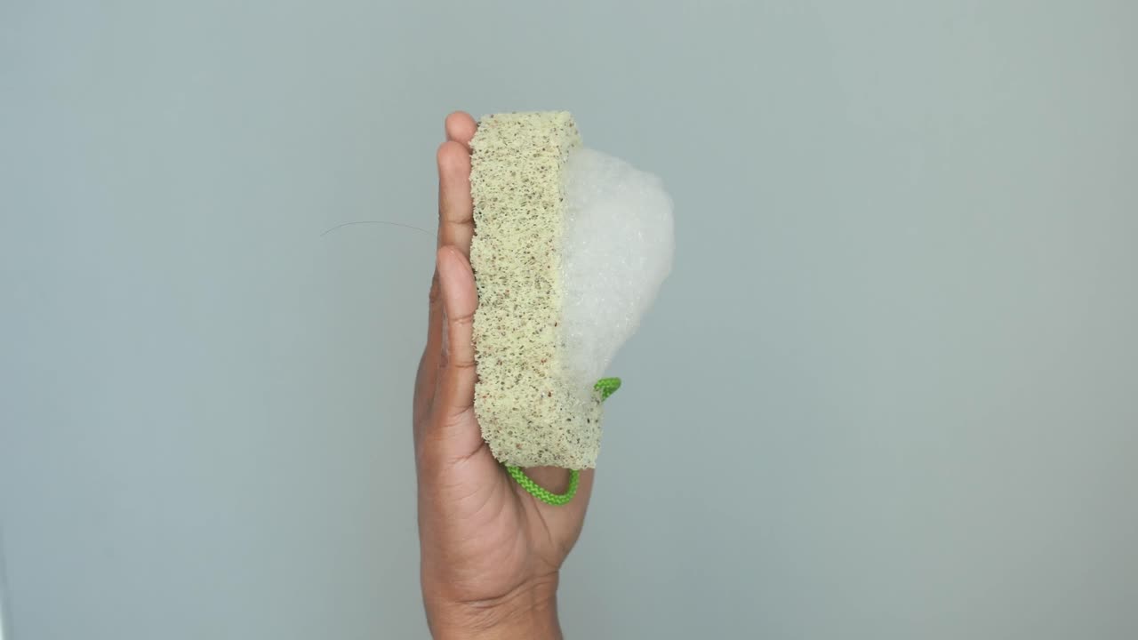 Hand Holding a Bath Sponge with Soap Foam