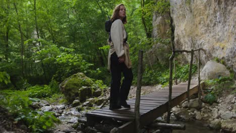 mujer caminando por un puente de madera en un bosque