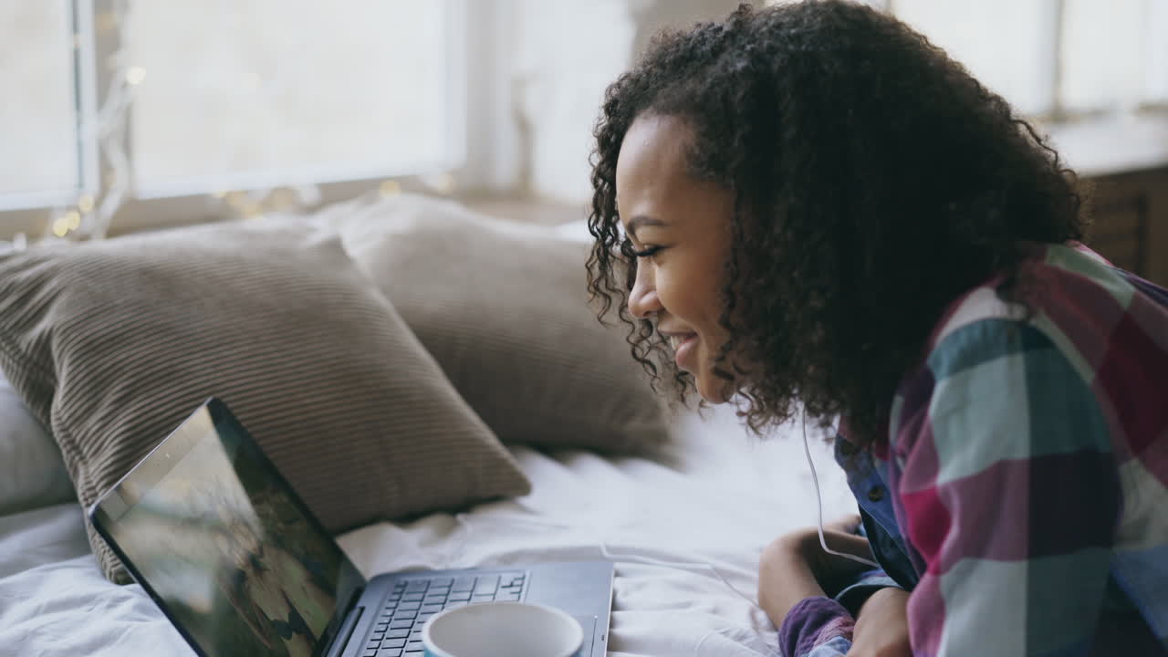 Young woman having a video call on laptop in bedroom