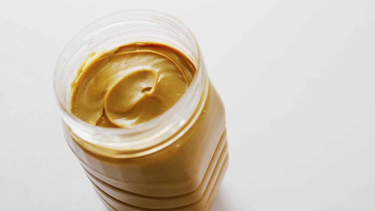 ⁇ 색 배경 에 땅콩 버터 가 있는 항아리 의 클로즈업 비디오
