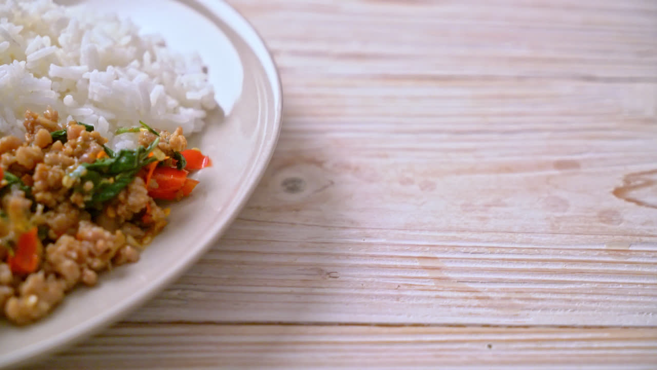 albahaca tailandesa salteada con carne de cerdo picada y chile sobre arroz coronado - estilo de comida local tailandesa