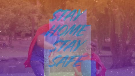 animation of words stay home stay safe over caucasian man and his son wearing capes