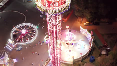 Aerial-shot-of-drop-tower-ride-at-amusement-park-at-night