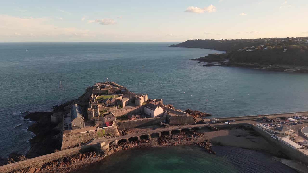 Castello Cornet, St Peter Port, Guernsey, ora d'oro, filmato aereo del castello e del mare blu calmo con vista su St Martins Point al sole pomeridiano in una giornata serena e limpida