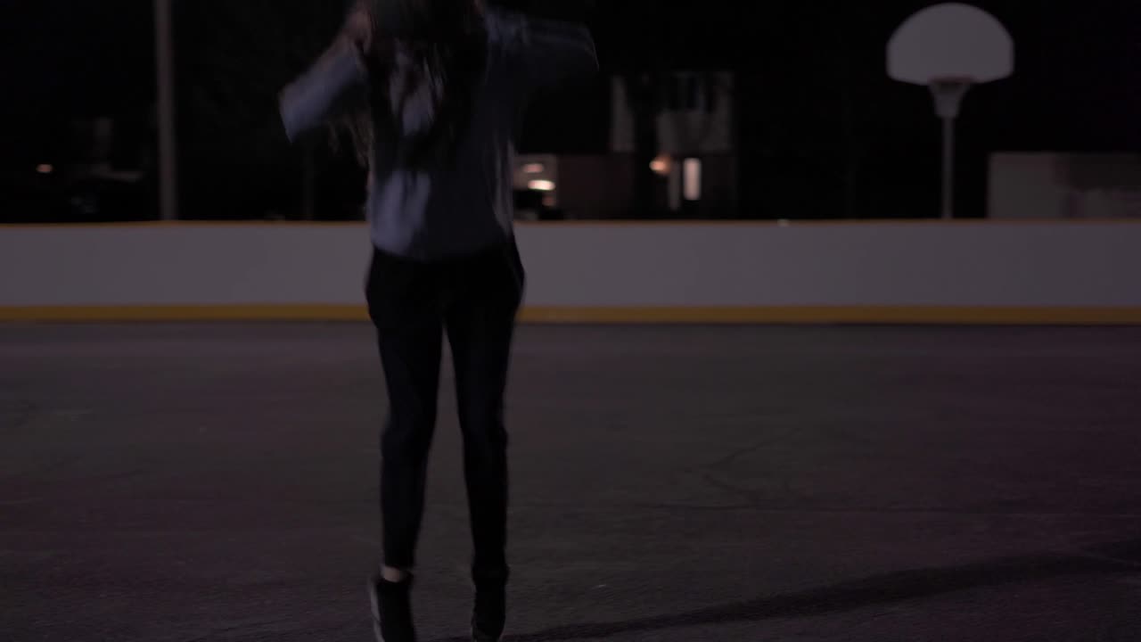 Slow motion jump shot at outdoor court at night, teenage girl with brown hair