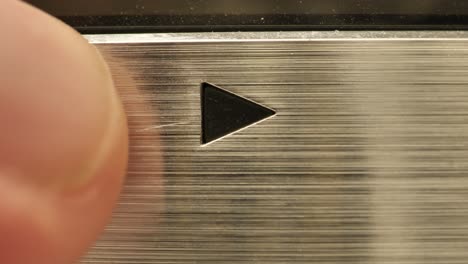 extreme close up of an old vintage vcr play button and a finger entering and pushing the button