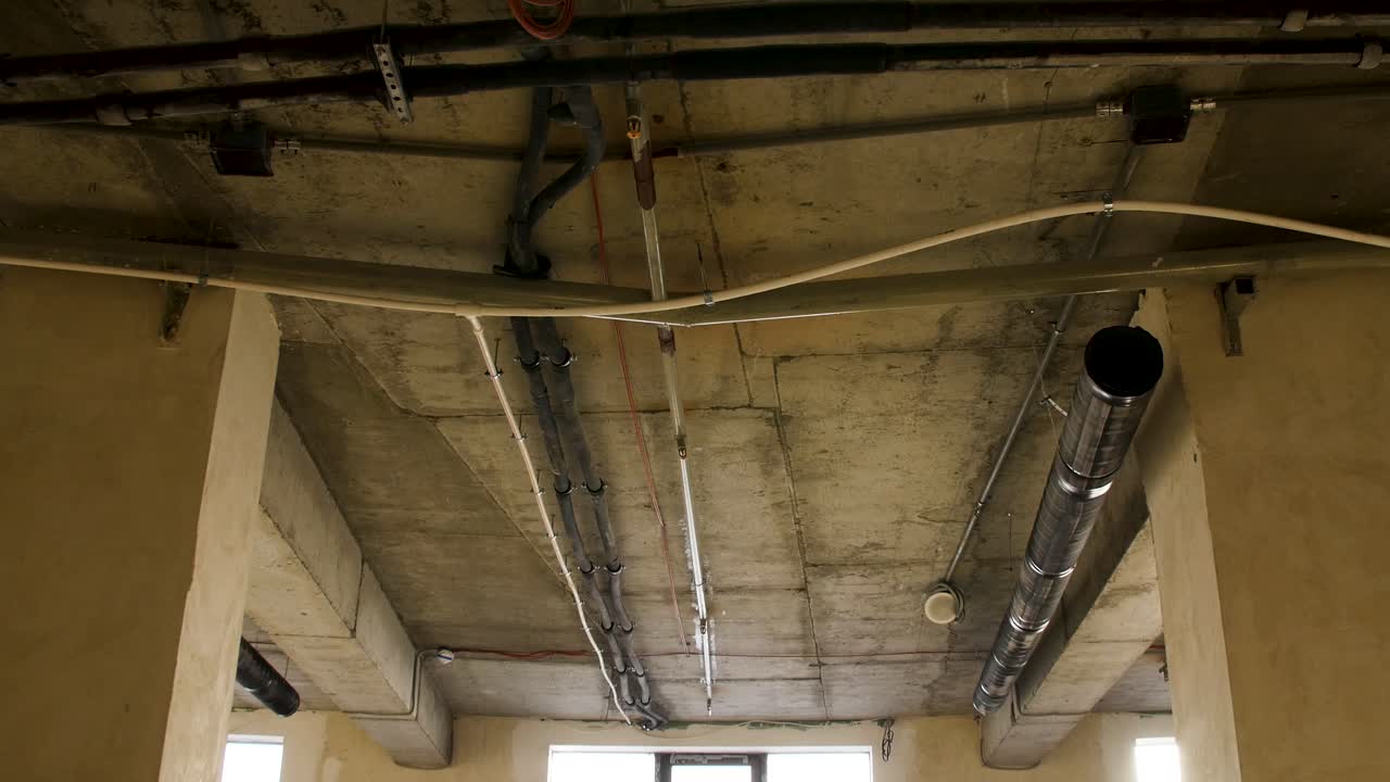 Interno di un edificio non finito con soffitto e impianti idraulici a vista