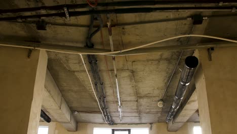 interior of an unfinished building with exposed ceiling and plumbing systems