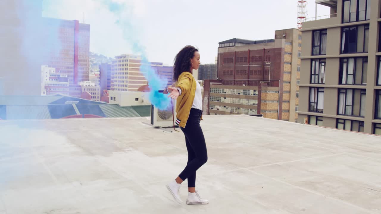 Joven mujer con estilo en una azotea urbana usando una granada de humo