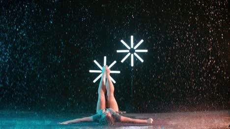 young caucasian female dancer performing modern dance, indoor rain effect