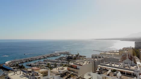 Drone-shot-rising-over-the-roof-tops-in-Marbella,-with-a-view-of-the-marina-and-the-sea