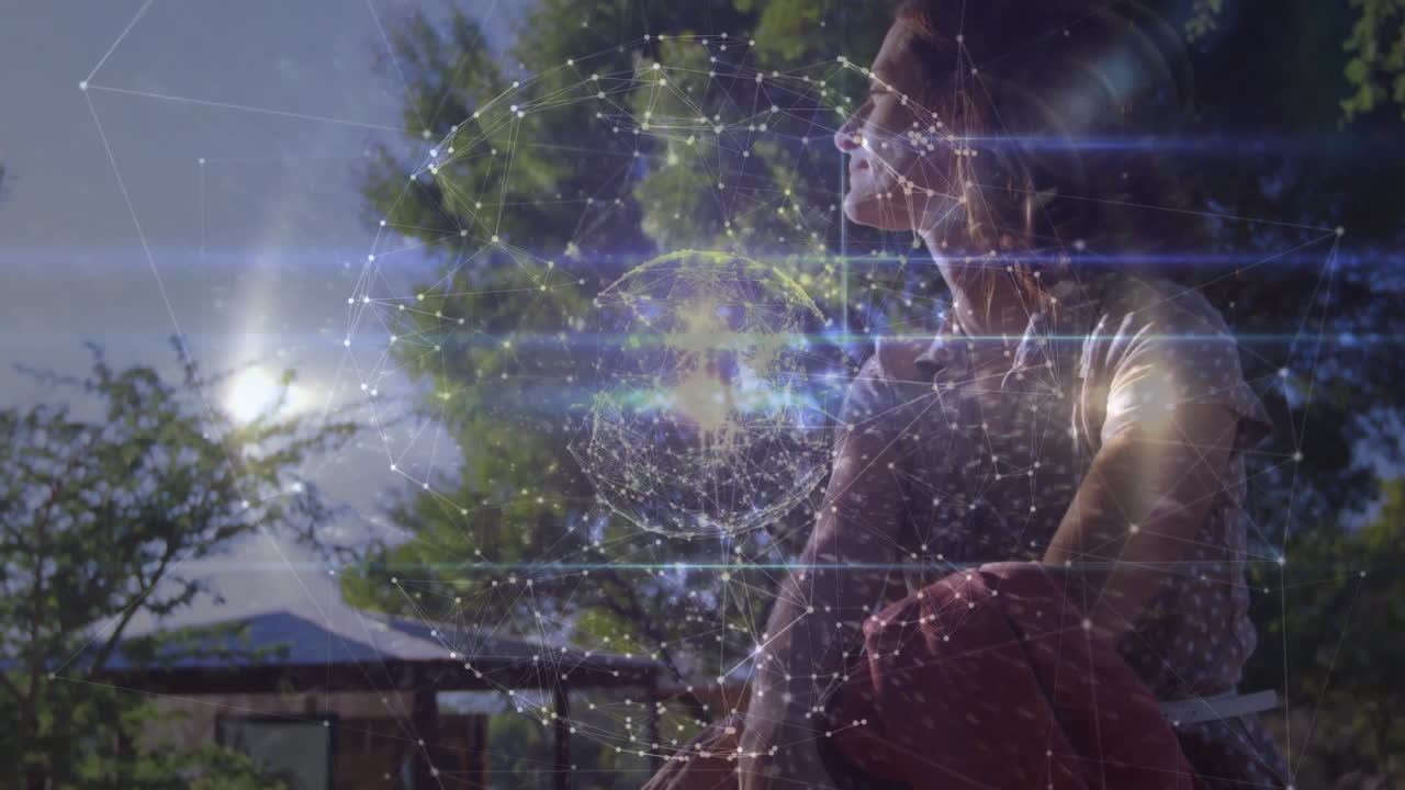 Mid-adult woman sitting on bench in park, visualizing network sphere for technology presentation