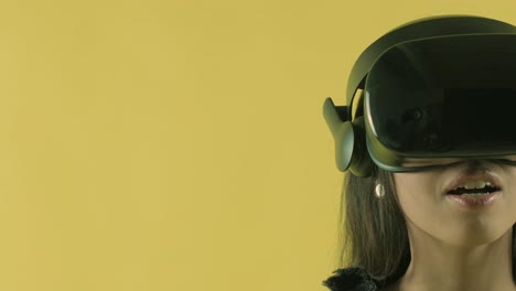 young woman looks around and wonders how amazing  in the vr world. virtual reality helmet on the yellow background. portrait