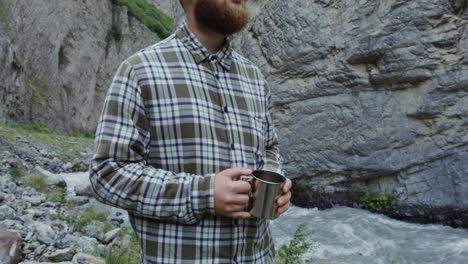 man enjoying a drink in a mountain canyon