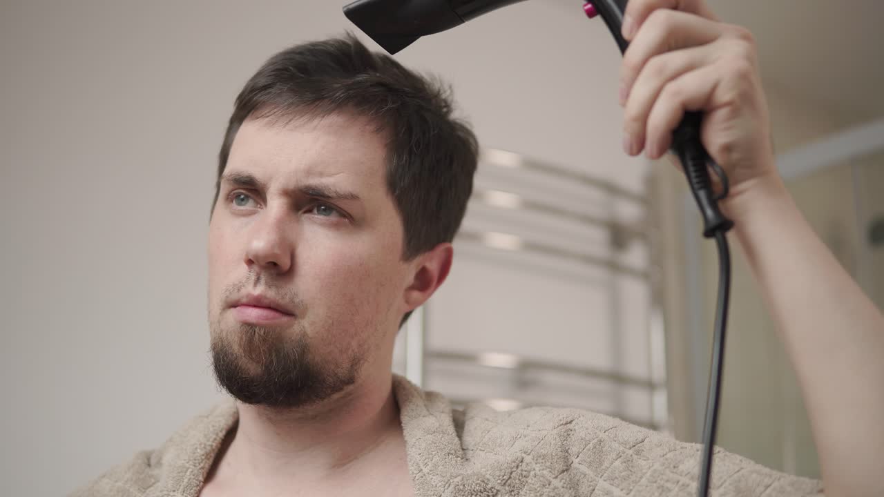hombre secando su cabello en el baño