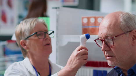 aged pharmacist using thermometer