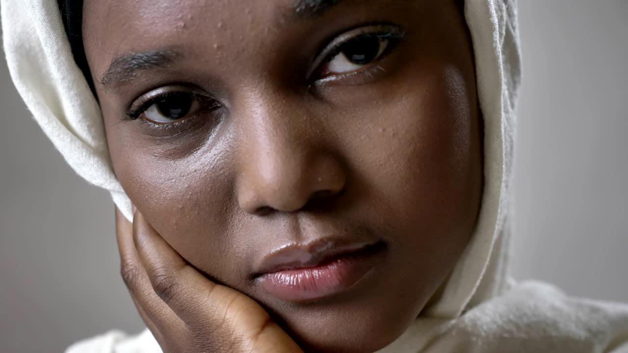 cara de joven triste chica musulmana africana en hijab está viendo en la cámara, concepto religioso, fondo gris