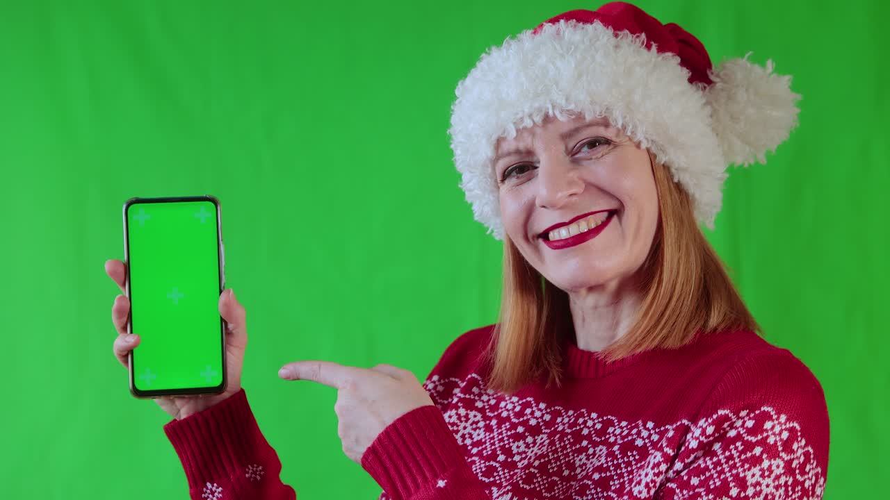 una mujer sonriente muestra un teléfono con pantalla verde.