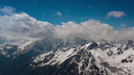 air flight through mountain clouds over beautiful snow-capped peaks of mountains and glaciers.