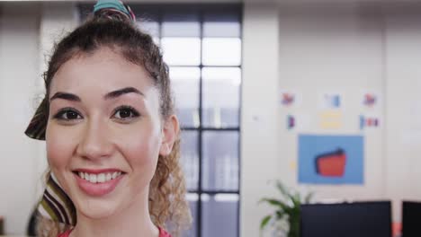 Portrait-of-happy-biracial-female-creative-at-casual-office,-with-copy-space,-in-slow-motion