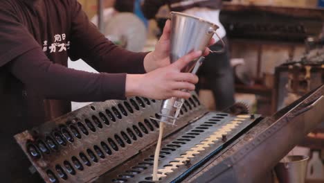 street food cook using stainless steel batter dispenser to pour batter in mold