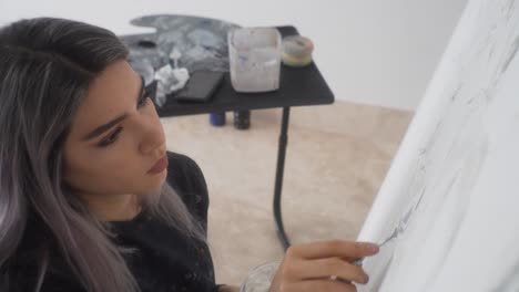 mujer latina se concentra en aplicar pintura sobre lienzo blanco