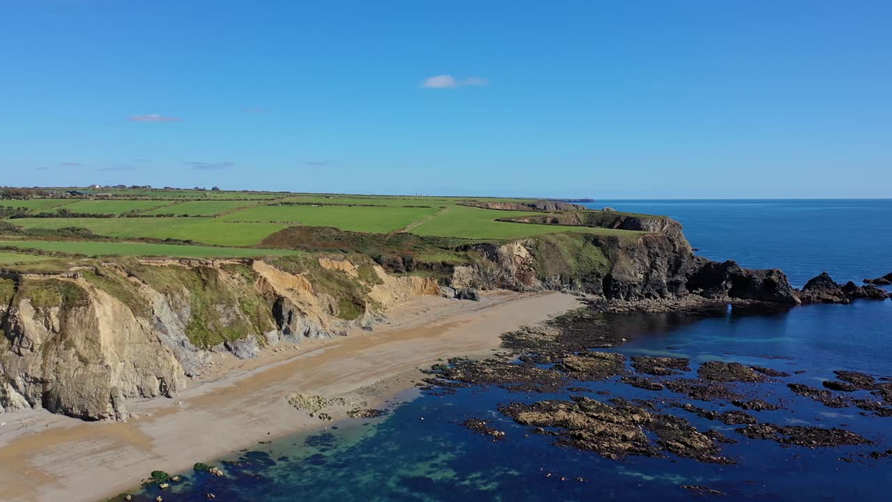 Luftfoto af den klippefyldte kystlinje, strand og klart vand i det sydlige Irland om sommeren