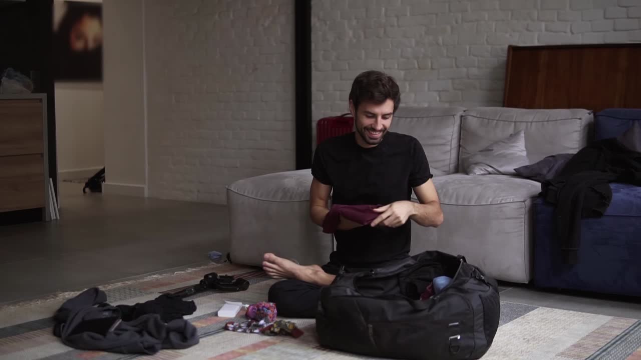 Portrait of a smiling man packing his back for travel in living room