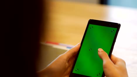 Close up young asian woman using smartphone with green screen at office. Hands scrolling, typing, touchscreen. Top view