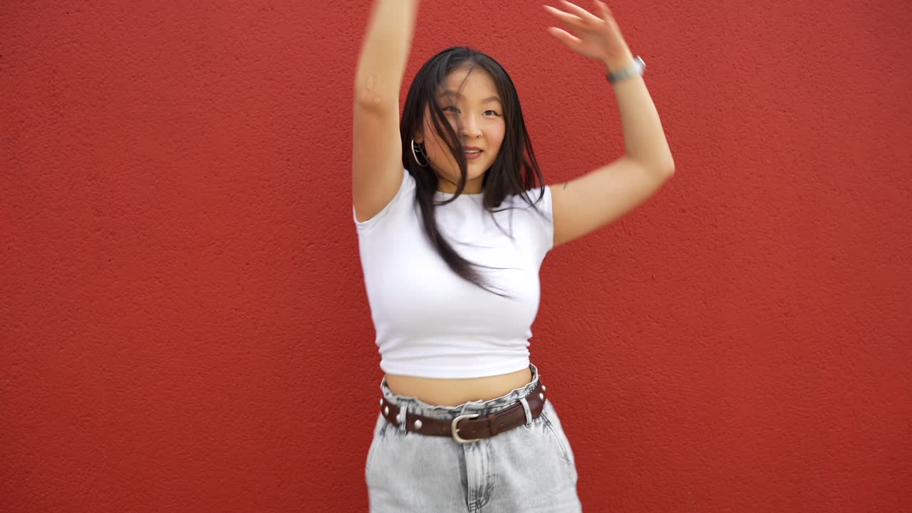 Woman dancing against a red wall