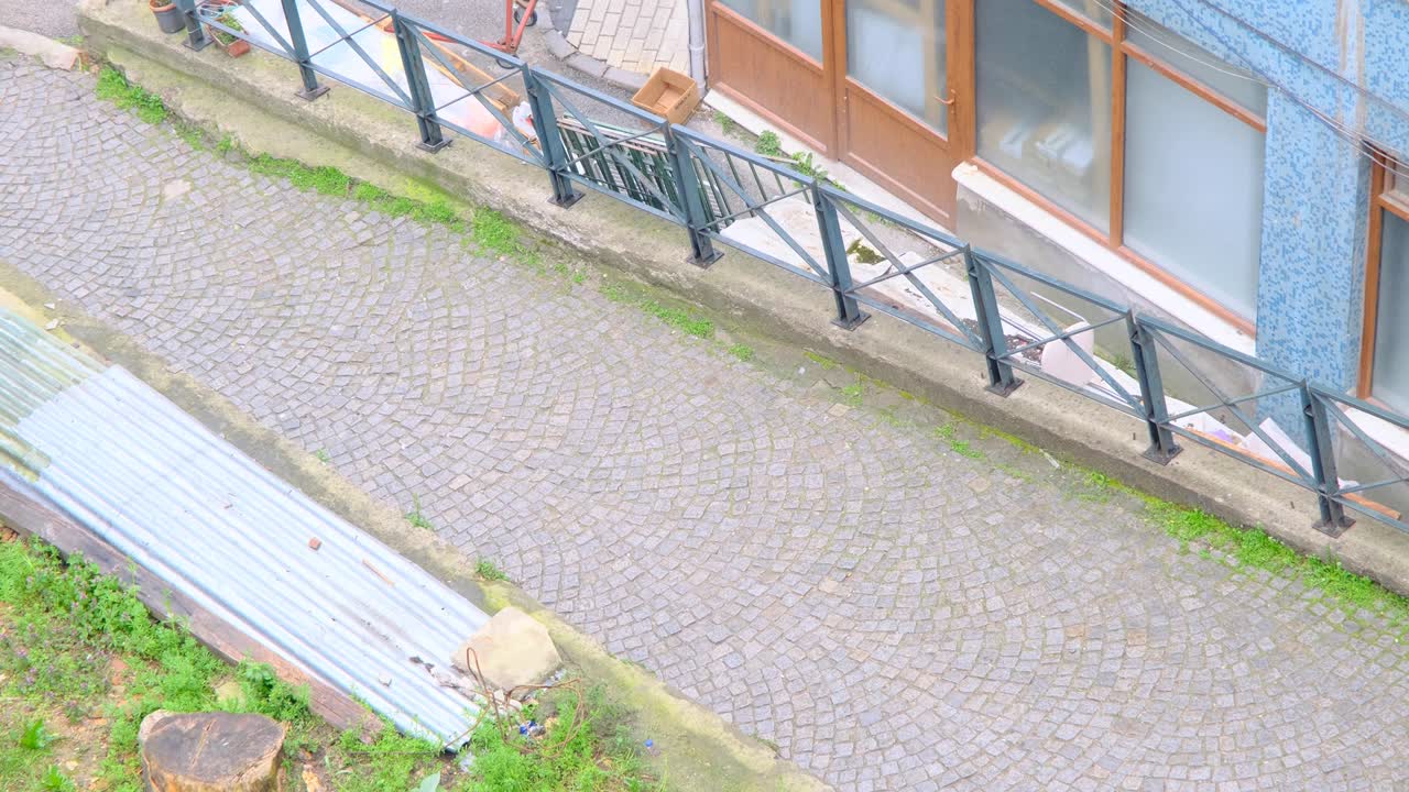 구름과 비가 오는 날 토파네 구역에서 비디오로 볼 수 있는 애비뉴의 공중 전망. 쇼핑 가방을 들고 아파트와 코블스톤 길을 돌아다니는 독신 여성.