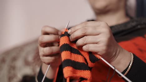 Footage-from-below-of-woman-knitting-with-red-and-black-wool-and-needle-crafts