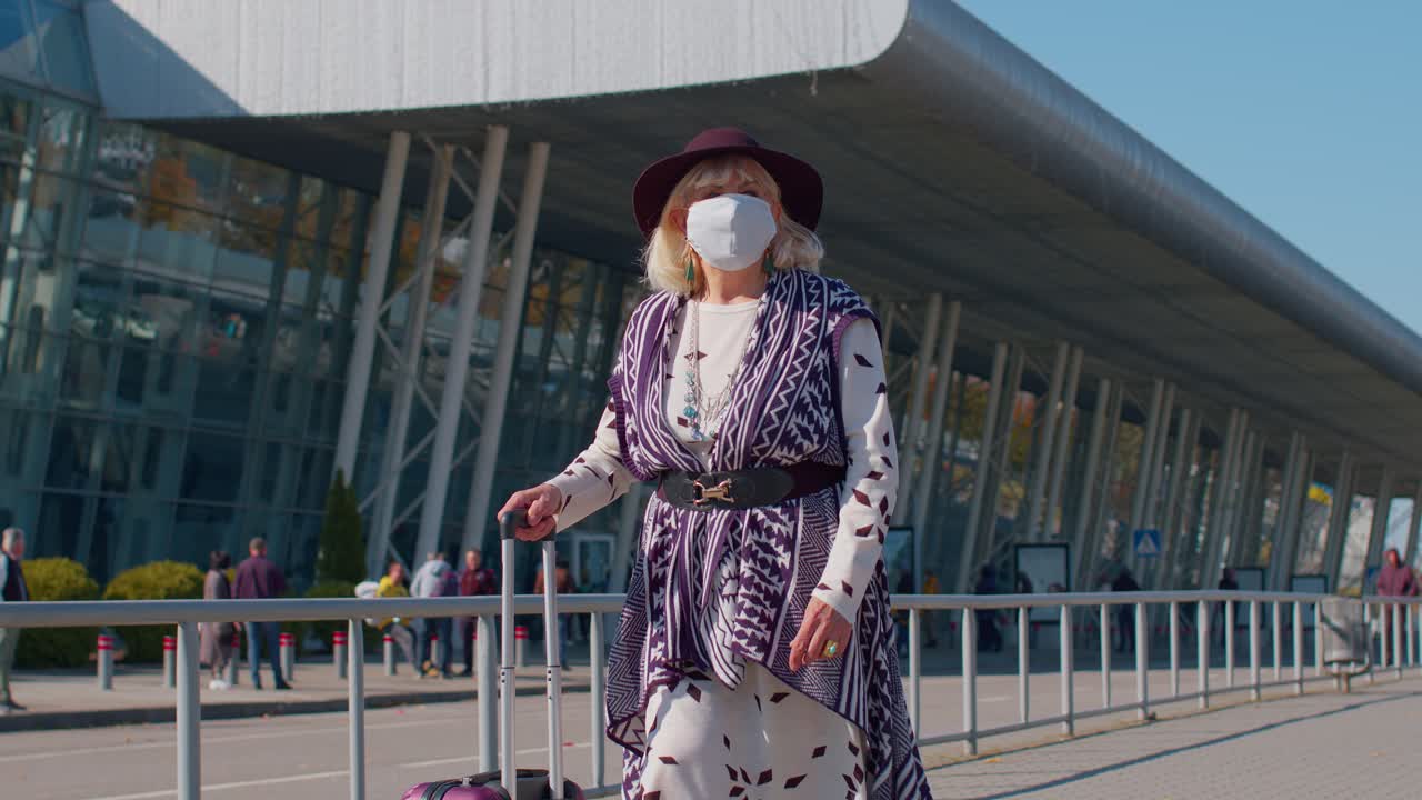 Nonna anziana, turista e pensionata, che indossa una mascherina protettiva per prevenire il coronavirus vicino all'aeroporto.
